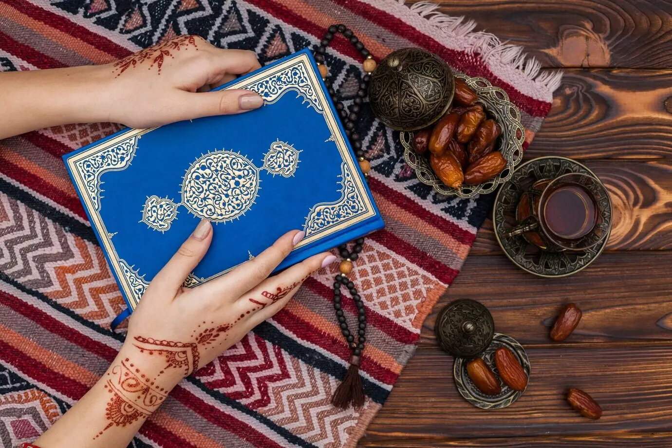 Eine Person mit Mehndi hält den Koran in der Nähe einer Teetasse.